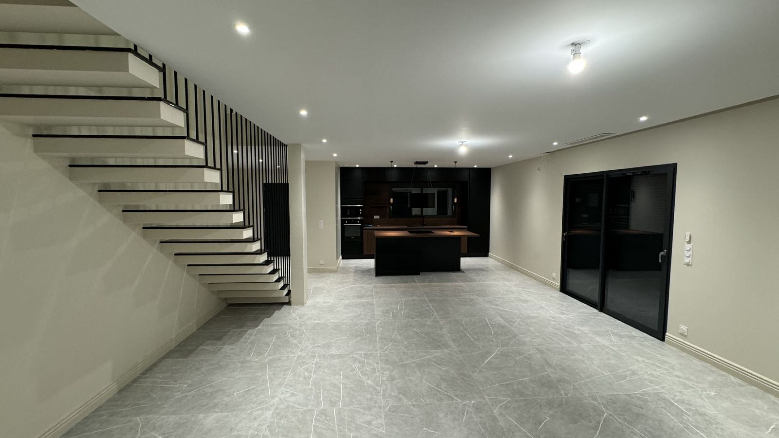 Pièce de vie d'une maison contemporaine avec escalier béton